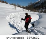 Woman walking in the snow with snowshoes on high mountain