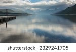 Small photo of Sunrise on Lake McDonald in Glacier National Park in Montana. Strong sky reflection on the still water. Empty dock extending into the lake.