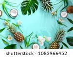 Summer tropical background with a space for a text, various fruits, green leaves and flowers arranged in a way that light shadows are fallen on the background surface, helping to keep some sum