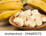 A banch of bananas and a sliced banana in a pot over a table.