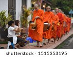 Small photo of Circa April 2018 - Luang Prabang, Laos: A group of mendicant buddhist monks begging bowl round in earnest.