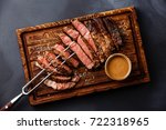 Sliced grilled meat steak Rib eye on meat fork and Pepper sauce on dark background