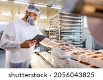 Small photo of A food inspector in a sterile white uniform is holding the tablet and looking at collected cookies. Food check is important if we want quality and healthy food.