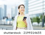 Small photo of A woman holding a smartphone on a street corner. Mobile communication. Taxi dispatch app.