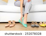 Trying on shoes by elegant lady sitting on white sofa background