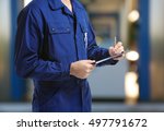 Mechanic in uniform with a clipboard and pen on gas station blurred background