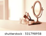 Set of cosmetics and vintage mirror on white table against light background