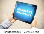 Small photo of Man holding tablet with text INSURANCE UNDERWRITER on screen outdoors