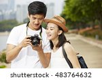 young asian couple tourists looking at camera's monitor checking pictures taken
