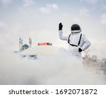 Small photo of An astronaut in a spacesuit raised his hand up and greets earthlings against the background of the circus building and the Kul-Sharif mosque in Kazan,Russia.The astronaut is exploring the planet Earth