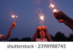 Small photo of Sparkler party. Girls have fun in nature with sparklers. Bengali flicker. Fun party with bright sparklers in hands. People fun night . Group happy young girls play sparklers on background of night sky