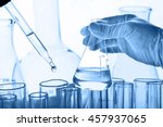 Flask in scientist hand with dropping chemical liquid to test tubes, science and medical research and development concept 