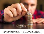 Small photo of Man counts his coins on a table. Personal finance, finance management, savings, thrifty or avarice concept.