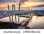 Aerial view of the New Goethals Bridge at sunset, spanning Arthur Kill strait between Elizabeth, New Jersey and Staten Island, New York. A conatiner ship navigates under the bridge.