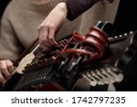 Small photo of Woman musician adjusting the tangents of her nyckelharpa in a close up on her hands as she prepares for a live performance or rehearsal
