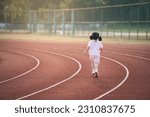 Small photo of Back side. Baby asian girl run jogging at running track, field at stadium. little female run sunset happy baby girl smiling. little girl running at sunset. cute baby girl running at running track.