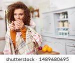 Young woman wrapped in blanket drinking hot tea 