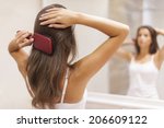 Young woman brushing healthy hair in front of a mirror 