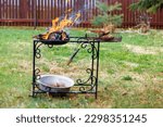 Small photo of a barbecue garden trolley and strong fire with a falling firebrand, concept of a reckless