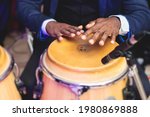 Small photo of Bongo drummer percussionist performing on a stage with conga drums set kit during jazz rock show performance, with latin cuban band performing in the background, drummer point of view