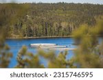 Small photo of View of circle sea fish farm cages and round fishing nets, farming salmon, trout and cod, feeding the fish a forage, with scandinavian lake landscape and forest island in the background in a summer