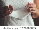 Small photo of Bride hands holding white medical face mask. Woman in wedding dress during the Coronavirus epidemic. Cancelled or postponed weddings caused by COVID-19 outbreak. Coronavirus concept, conceptual photo.