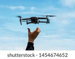 Hands reaching for drone against blue sky