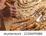 Wood carving. Carpenter's hands use chiesel. Senior wood carving professional during work. Man working with woodcarving instruments