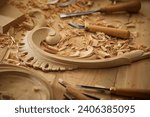 Small photo of Experienced carpenter shapes wood with a chisel. Wooden table with a set of different chisels for woodcarving.