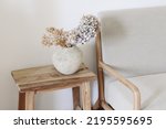 Small photo of Fall still life photo. Rustic textured vase with dry hydrangea flowers on old wooden bench. Blurred linen mid century sofa background. White wall. Scandinavian interior. Boho elegant home decor.