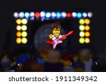 Small photo of Lorrach, BW Germany - February, 06 2021: Lego minifigure popstar with red guitar on th stage with light bulbs. Editorial illustrative image of entertainment concert. Studio shot.