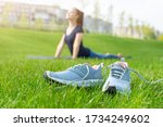 Close up sports shoes sneakers on green grass and Yoga girl on background. Sports in the open air.