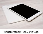 White digital tablet with pen and notebook on the table