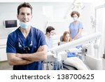 A portrait of a dentist with his team working in the background