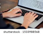 Stock photo of female hands touching keyboard of laptop with words on screen. Crop office worker typing document using modern gadget. Concept of business