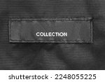 Clothing label says collection stitched on black fabric background closeup