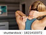 Sports injury concept. Athletic woman feeling pain in her neck against blurred background. Pain after home workout