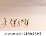 Miniature People exercising while running in a group on the beach. Living an active lifestyle concept
