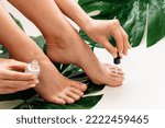 Small photo of Closeup of wet female feet and bottle of nourishing cuticle oil with dropper