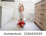 An Adorable young baby child sitting and learning how to use the toilet