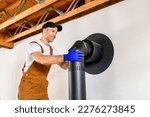 Small photo of A male worker preparing a chimney installation for a modern, energy saving heating stove.