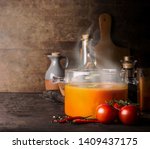 Small photo of Glass cooking pot with hot tomato soup and blow off steam standing on rustic kitchen table with ingredients. Copy space. Healthy eating and homemade cooking