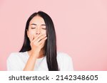 Portrait Asian beautiful young woman emotions tired and sleepy her yawning covering mouth open by hand, studio shot isolated on pink background, Thai female insomnia concept