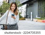 Portrait of beautiful smile business woman commute her bicycle outdoor using smartphone at urban, bike go to work office, Asian businesswoman standing on city street with bicycle holding mobile phone
