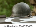 An M1 US infantry helmet from the Second World War lies on the bonnet of a military vehicle.