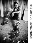 Small photo of Punk rocker or redneck sits on the floor and smoke in a messy house.