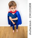 Small photo of sad little superhero boy feeling denigrated, frustrated, scared, disappointed by parenthood and education, high angle view
