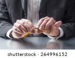 Small photo of businessman breaking a pencil out of nervosity at the office