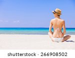 Young woman on the beach. Girl sitting on sand and sunbathing. Relaxation, rest, vacations, holidays, summer fun, enjoy life concept