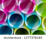 Small photo of Colourly striped plastic drinking straws, black underground background